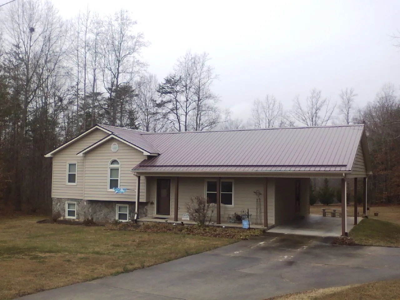 Burgundy metal roof on a tan split level home with an attached carport in Ansonia