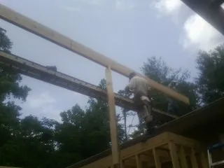 Carpenter setting a ridge beam over a new addition frame — Ice Dam Removal by Roofing Brothers in Ansonia