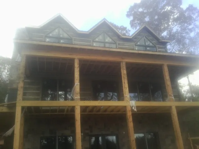 Dormers and porch framing on a large log home under construction — Roof Coating work by our crew in Ansonia