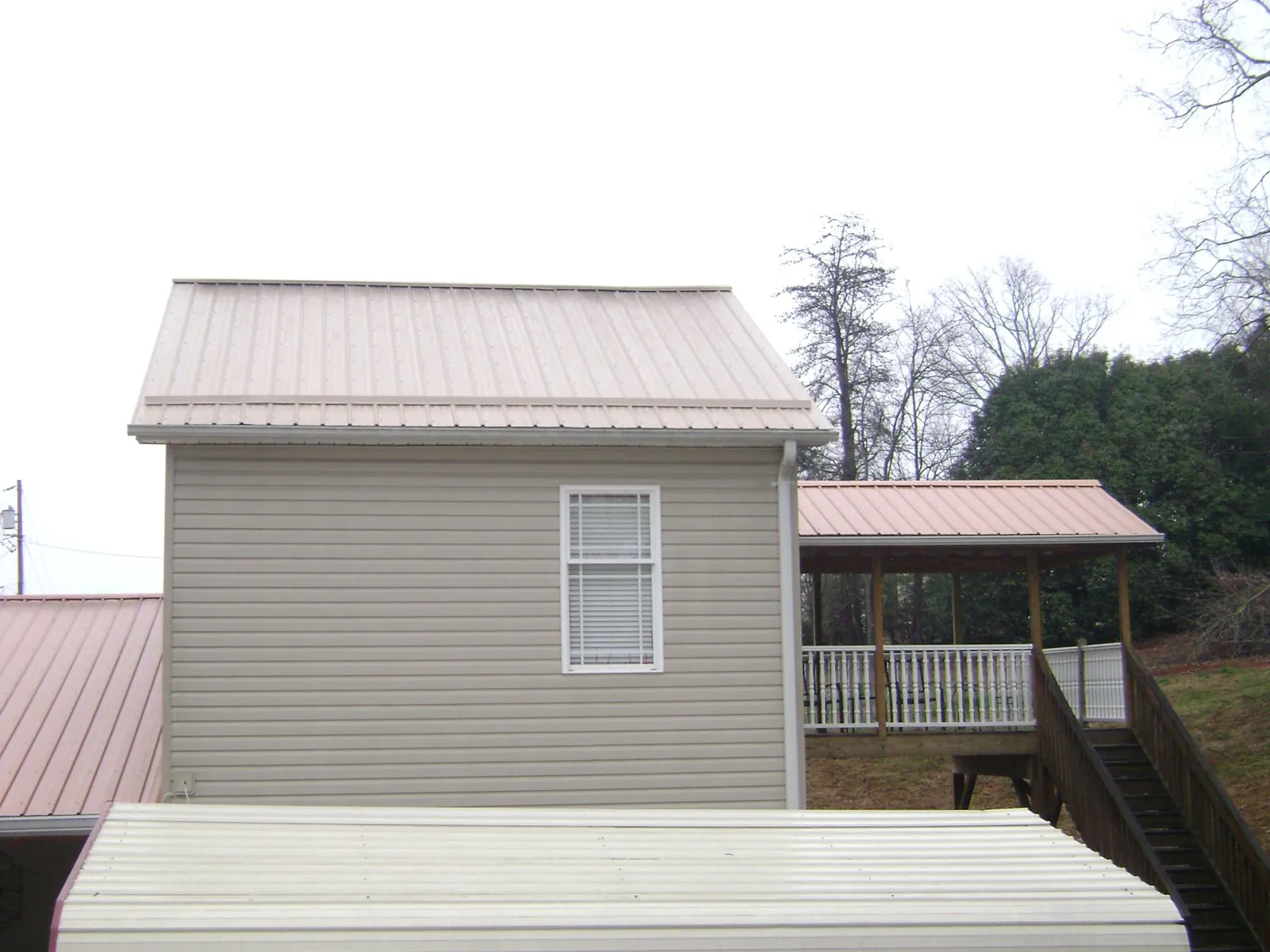 Tan metal roofs on a two story addition and attached porch, from a Roof Replacement job in Ansonia