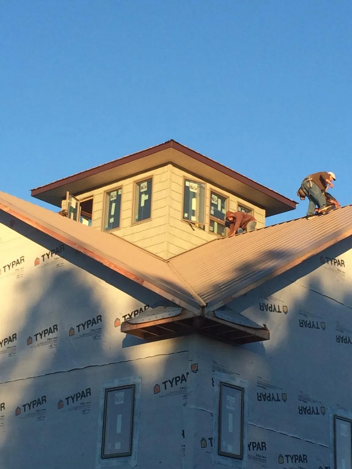 Roofers working around a rooftop cupola on a new metal roof at sunset — Roof Waterproofing in Ansonia by Roofing Brothers